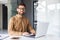 Portrait of successful man at workplace inside office, experienced smiling businessman in shirt smiling and looking at