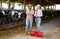 Portrait of successful young couple of professional breeders standing in cowshed