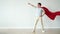 Portrait of super hero in fluttering red cape and mask standing with raised arm