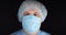 Portrait, surgeon. The doctor stands in a surgical cap, medical mask and gown on a black isolated background. a surgeon