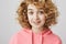 Portrait of surprised enthusiastic european woman with frizzle hairstyle, smiling with lifted eyebrows, expressing