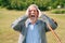 Portrait of a surprised grayhaired stylish adult European grandfather against the background of nature