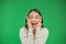 Portrait of surprised, joyful young asian woman showing thumbs up over green background