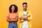 Portrait of surprised sarcastic african american woman with afro hairstyle standing with cute boyfriend crossing arms on