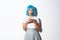 Portrait of surprised silly asian girl looking coquettish at camera, holding cake on plate, wearing blue anime wig