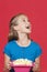 Portrait of surprised young girl holding popcorn container against red background