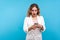 Portrait of surprised young woman reading shocking message on cellphone, unbelievable news about sales. blue background