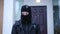 Portrait of suspicious Caucasian masked man looking around standing on snowy winter day outdoors. Young male robber at