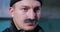 Portrait of suspicious man in black knitted hat and with thick graying mustache frowned at something squinting, then