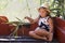 Portrait of sweet little girl in a dress with a hat while sitting in a boat on the lake