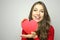 Portrait of a sweet perfect girl smiling at camera with heart shaped paper in her hands. Valentine`s Day concept.