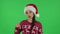 Portrait of sweety girl in Santa Claus hat is reporting and telling a lot of interesting information. Green screen