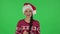Portrait sweety girl in Santa Claus hat seductively smiling and gesture threatens by shaking index finger. Greenscreen