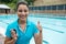 Portrait of swim coach holding stopwatch and showing thumbs up near poolside