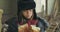 Portrait of a Syrian refugee in hat with earflaps greedily eating the loaf of bread. Hungry homeless child living on the