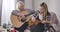 Portrait of talented Caucasian grandmother and granddaughter playing music indoors. Blond woman playing guitar as teen