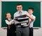 Portrait of a teacher dressed in business suit with folders, documents and briefcase, posing with schoolboy and schoolgirl at