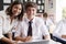 Portrait Of Teacher Helping Pupil Using Computer In Classroom