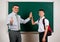 Portrait of a teacher and schoolboy playing at blackboard background - back to school and education concept