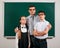 Portrait of a teacher, schoolboy and schoolgirl with old fashioned eyeglasses posing on blackboard background - back to school and