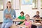 Portrait, teacher and woman with children in classroom, smile and holding folder. Happiness, female educator and
