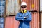 Portrait of technician with blue uniform hold wrench and stand with action of confident in front of cargo shipping containers