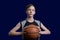 Portrait of a teen basketball player. The guy in the black t-shirt holds the ball in his hands. The concept of a sports poster or