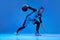 Portrait of teen girl, basketball player in motion, dribbling ball isolated over blue studio background in neon
