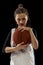 Portrait of teen girl, concentrated basketball player in uniform posing isolated over black studio background