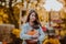 Portrait of teen girl with long hair posing with pumpkin at the open farm market place. Autumn background