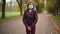 Portrait of teen girl putting on coronavirus face mask standing on alley outdoors. Adolescent Caucasian teenager posing