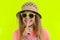 Portrait of teen girl in sunglasses and straw hat with a forefinger near the lips, showing silence sign, secret gesture, yellow