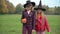 Portrait of teen girls with Jack-o-Lantern in witch hats walking holding hands talking outdoors. Dolly shot of Caucasian