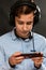 Portrait of a teenage boy in headphones playing a game on his smartphone. Vertical. Black background. Concept of entertainment and