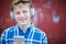 Portrait Of Teenage Boy Wearing Wireless Headphones And Listening To Music In Urban Setting