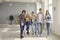 Portrait of teenage classmates with books and gadgets in high school hallway