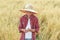 Portrait of teenage farmer boy is checking oat seeds in cupped palms at ripe field