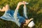 Portrait of teenage girl 14 years old lying on the grass. Girl in dress hat, in her headphones holds a smartphone, listens to musi