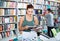 Portrait of teenage girl customer looking at open book standing