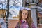 Portrait of a teenage girl with glasses, with a rucksack and white bows on a walk in the park after school