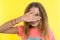 Portrait of teenage girl peeps through fingers. Yellow studio background