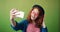 Portrait of teenage girl taking selfie with smartphone waving hand smiling