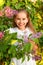 Portrait of a teenage girl with a wide open smile in lilac bushes in a white dress