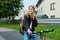 Portrait of teenage student girl with backpack on bicycle talking on phone