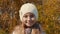 Portrait teenager girl in cap on yellow foliage of autumn trees close up