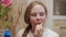 Portrait teenager girl eating potato chips on home kitchen. Close up face freckled girl teenager eating crisp chips on