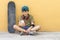 Portrait of a teenager sitting on the floor on a street road chatting ( Skateboard on the wall )