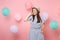 Portrait of tender fascinating young woman wearing straw summer hat and blue dress keeping hand near face on pink