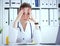 Portrait of tensed doctor sitting at the workplace in the hospital with hand on forehead in hospital