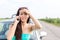 Portrait of tensed woman using cell phone against broken down car on road